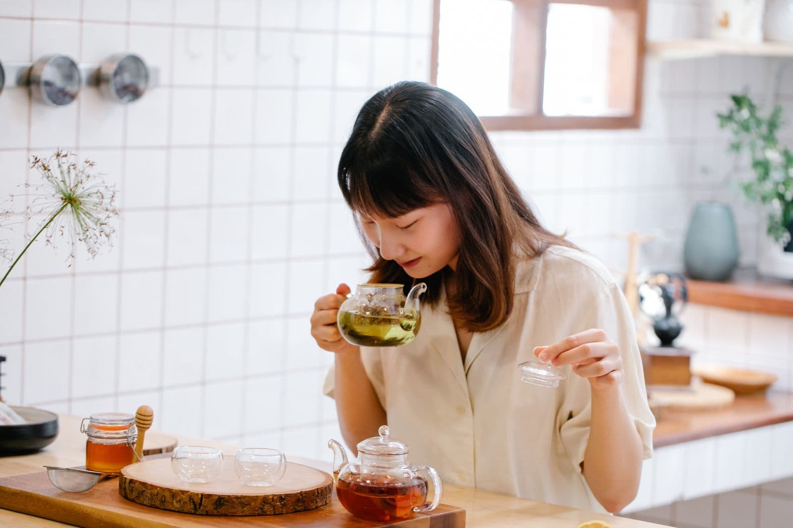 Asian woman preparing herbal tea in a bright home kitchen
